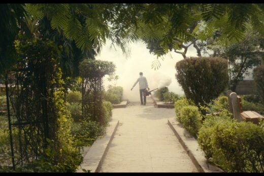 Hahmo seisoo keskellä puutarhan läpi kulkevaa polkua