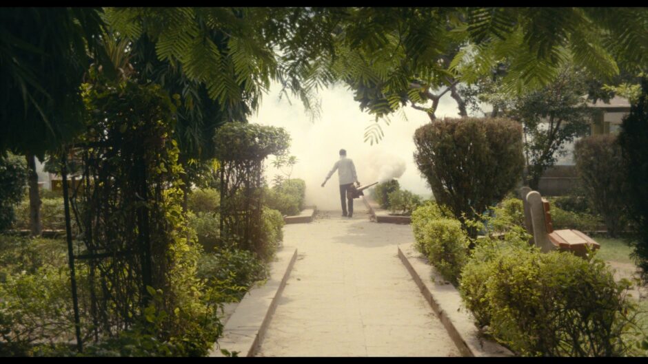 Hahmo seisoo keskellä puutarhan läpi kulkevaa polkua
